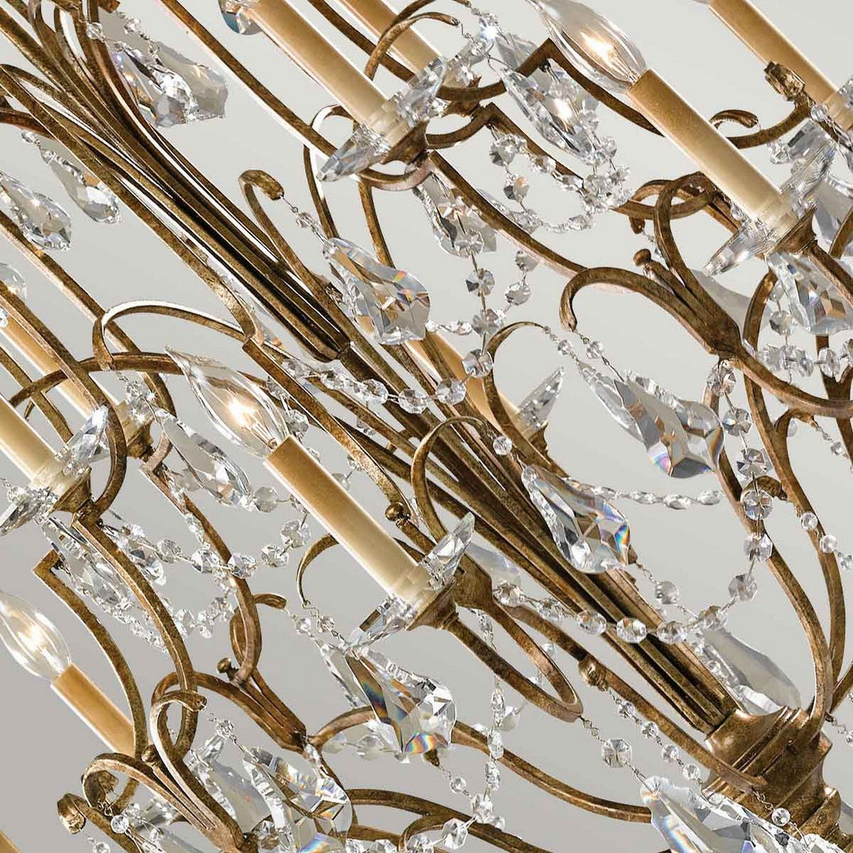 Close-up of the Valentina 12 Light Chandelier - Oxidized Bronze, featuring intricate metalwork in a rich bronze finish, adorned with large teardrop-shaped crystals and crystal bobeches. The chandelier's candle-like bulbs and elegant curves create a luxurious, sparkling appearance.