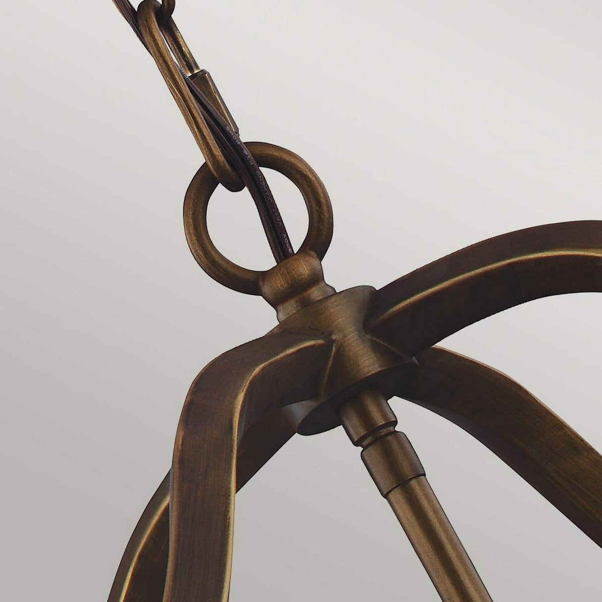 Close-up of the Yarmouth 4 Light Chandelier - Painted Aged Brass, featuring a vintage-style bronze design with a circular metal frame and connecting chain, elegantly displayed against a plain light background.