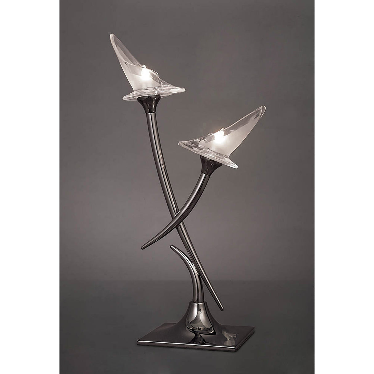 The Flavia 2 Light Table Lamp - Black Chrome features two curved metallic stems with clear flower-shaped glass shades, creating a soft glow. Its artistic, minimalist design includes a sleek black chrome base for a modern look.
