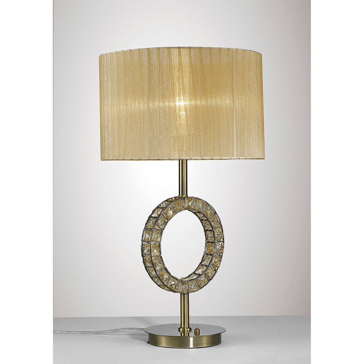 The Florence Round 1 Light Crystal Table Lamp features a brass base, a decorative ring with crystal accents, and a large pleated cream fabric shade. It is displayed on a flat white surface against a light background.