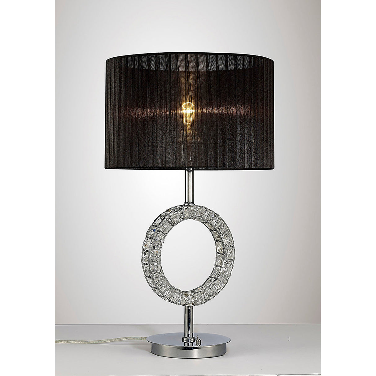 The Florence Round 1 Light Crystal Table Lamp features a textured chrome base with an open circular design and a black fabric shade. When switched on, it casts a warm, ambient light for a modern touch.