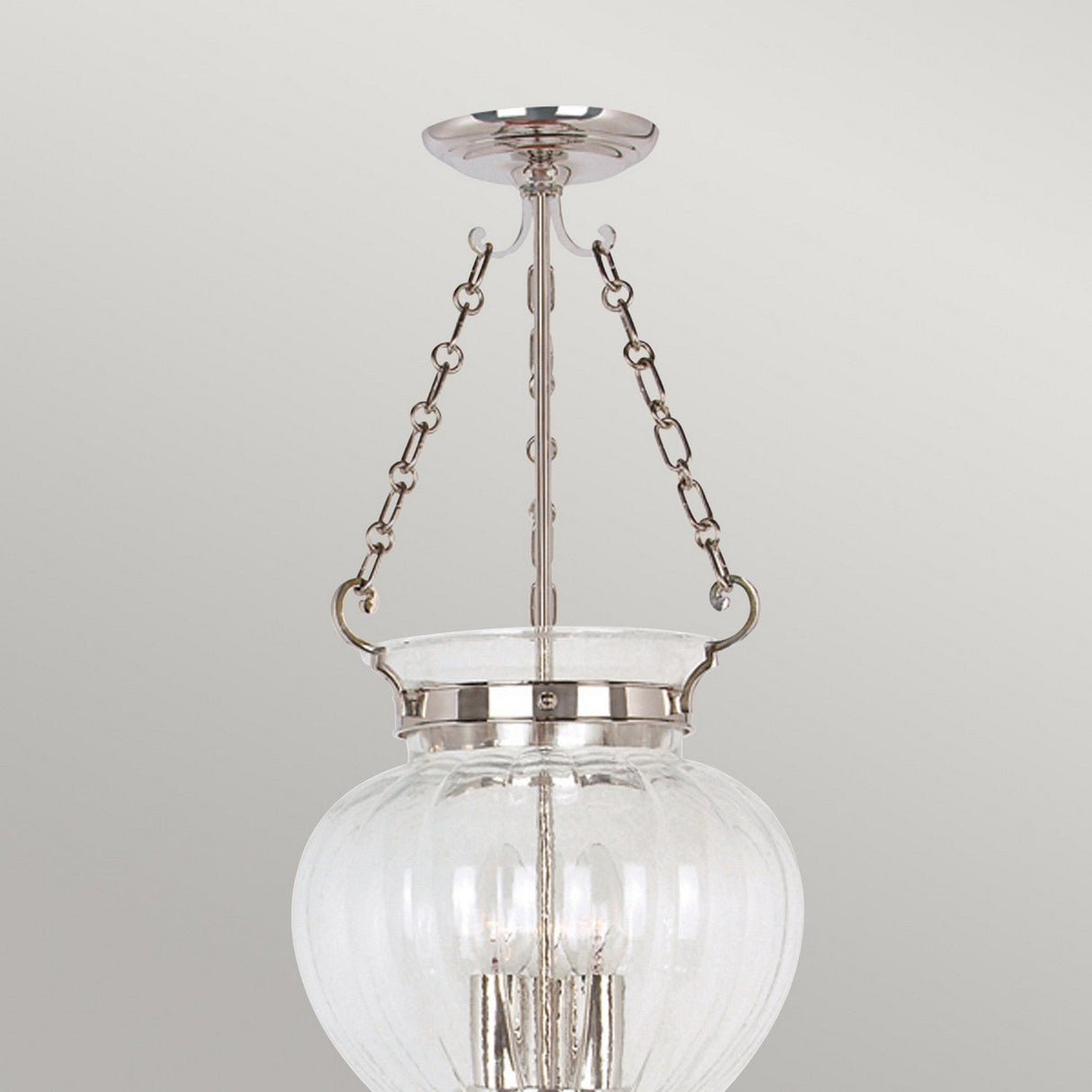 The Finsbury Park 3 Light Medium Chandelier in Polished Nickel is a contemporary chandelier featuring a clear glass globe, polished nickel accents, and a modern design with visible light bulbs. It is suspended by two metal chains.