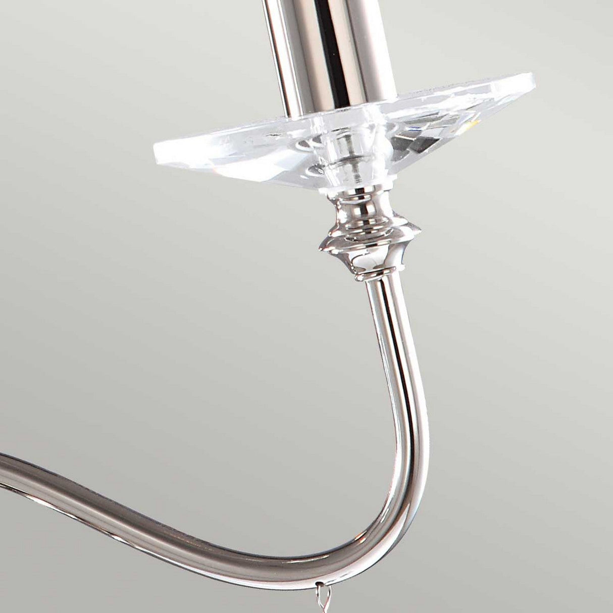 Close-up of a polished nickel arm from the Finsbury Park 3 Light Chandelier, showcasing its modern curved design. It features a crystal-like accent near the top, set against a light gray background.