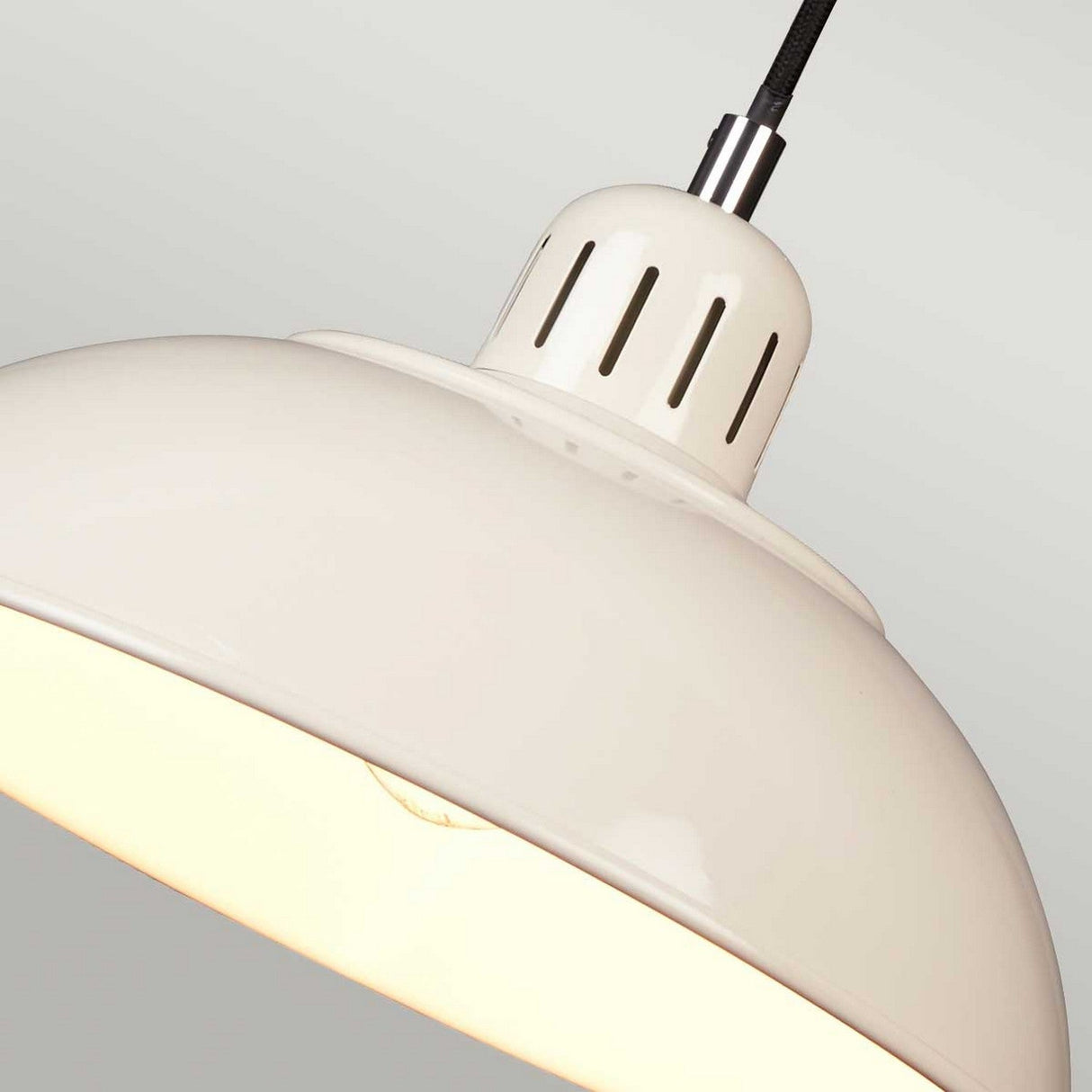 Close-up of the Franklin 1 Light Pendant - Cream, showcasing a cream-colored, dome-shaped design with a smooth finish. This retro-inspired diner light is illuminated, casting a warm glow. Featuring a colored spun shade, it is height-adjustable and suspended by a black cord against a light gray background.