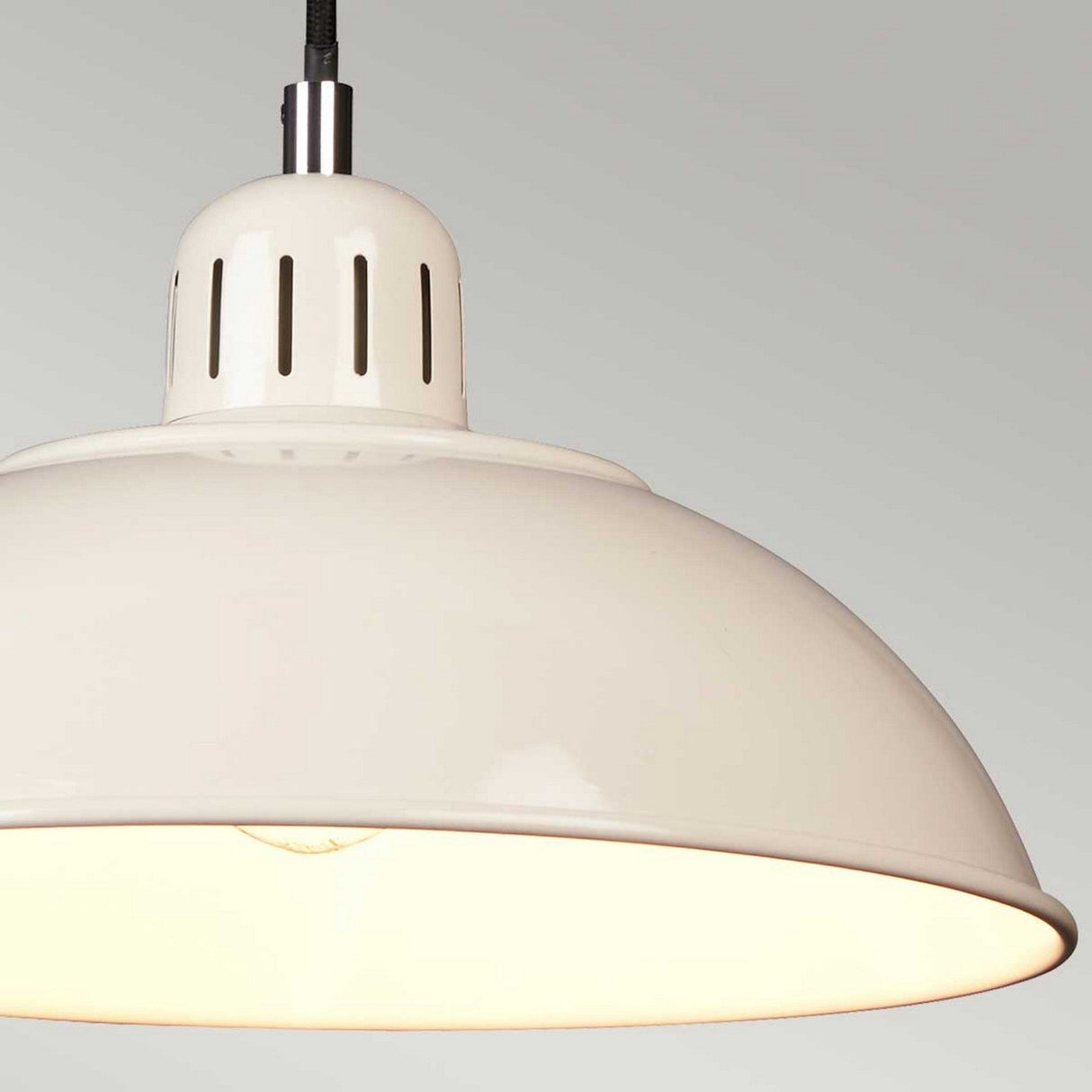 Close-up of the Franklin 1 Light Pendant in cream, showcasing its retro-inspired design with a dome-shaped, height-adjustable hanging light fixture. It features a glossy finish and a perforated top section for ventilation. The light is illuminated, casting a warm glow against the neutral gray background.