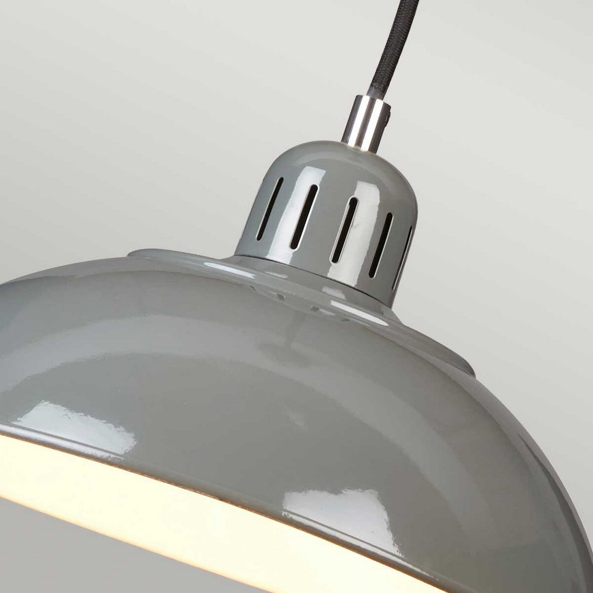 Close-up of the Franklin Pendant Light - Grey, with a large, glossy surface and metal fixture. The light is illuminated, casting a soft glow across its reflective exterior. It seamlessly complements industrial interiors and echoes retro diner aesthetics while suspended from a black cord against a neutral backdrop.