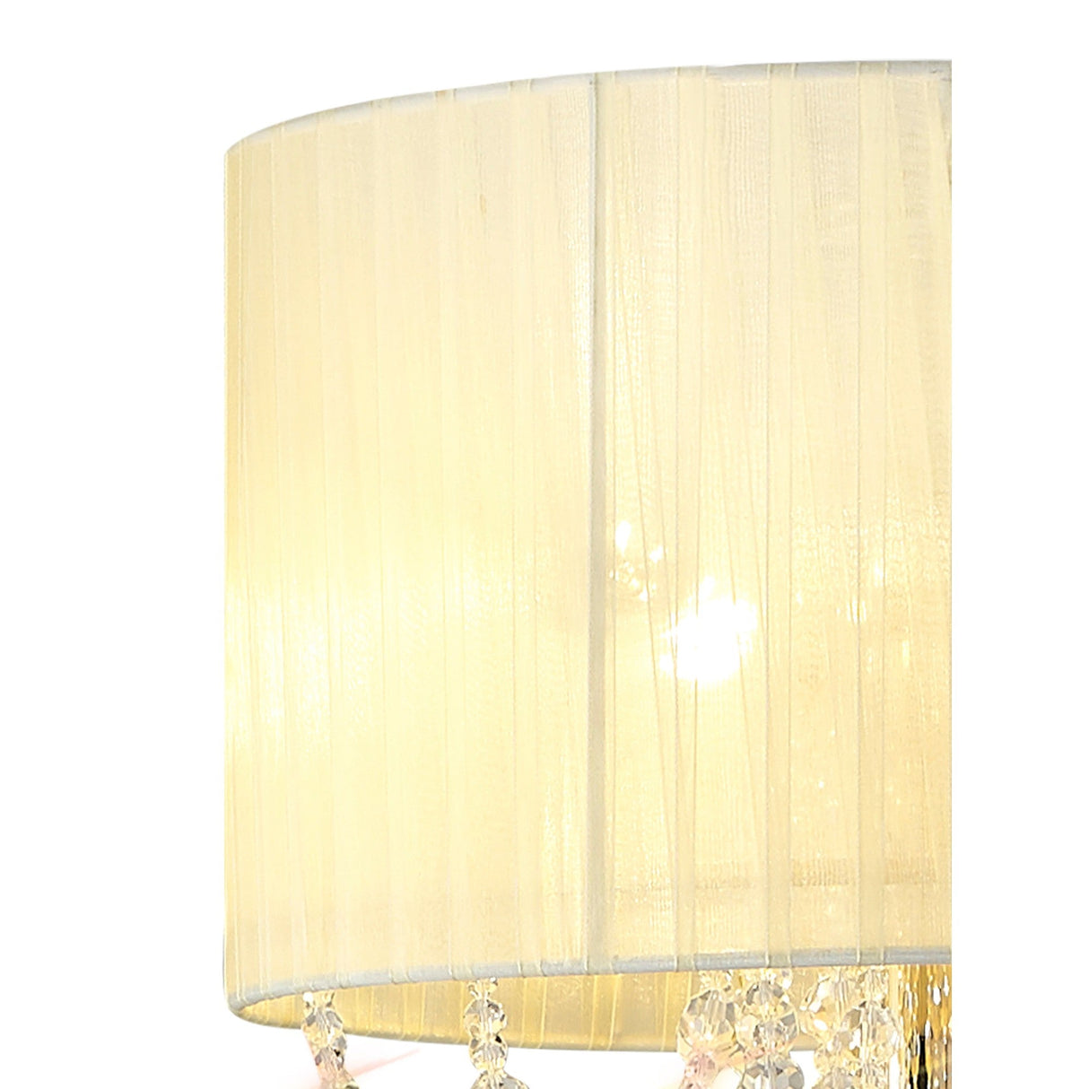 Close-up of the Freida 3 Light Crystal Floor Lamp in gold. Its cream, sheer fabric shade glows warmly, while small crystal-like accents hang from the edge, adding elegance. Set against a plain white background.