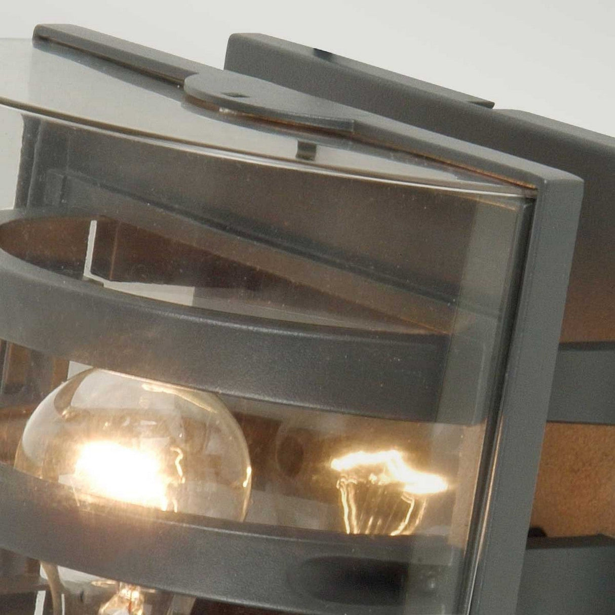 The Frida Outdoor Wall Light - Graphite showcases a modern lighting design with a light bulb encased in a sleek, die-cast aluminium box, making it perfect for an outdoor wall light setup.