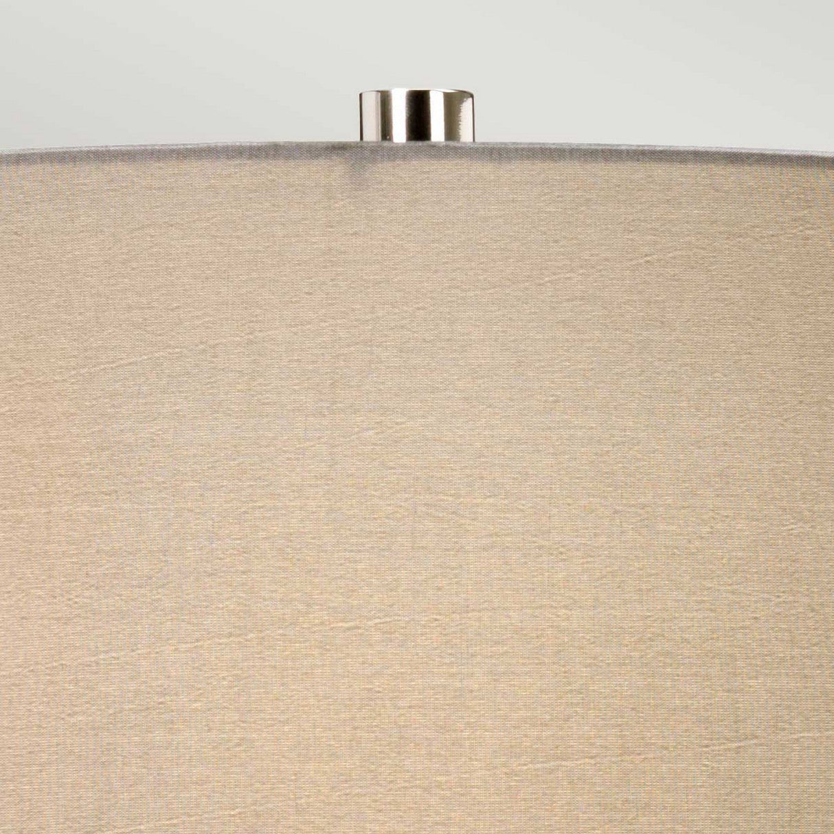 Close-up of the beige fabric shade with a smooth texture on the Fulwell 1 Light Table Lamp in White Gloss & Matt Grey. The silver metal finial adds a touch of sophistication, while the plain light gray background enhances the modern elegance of this contemporary lighting design.