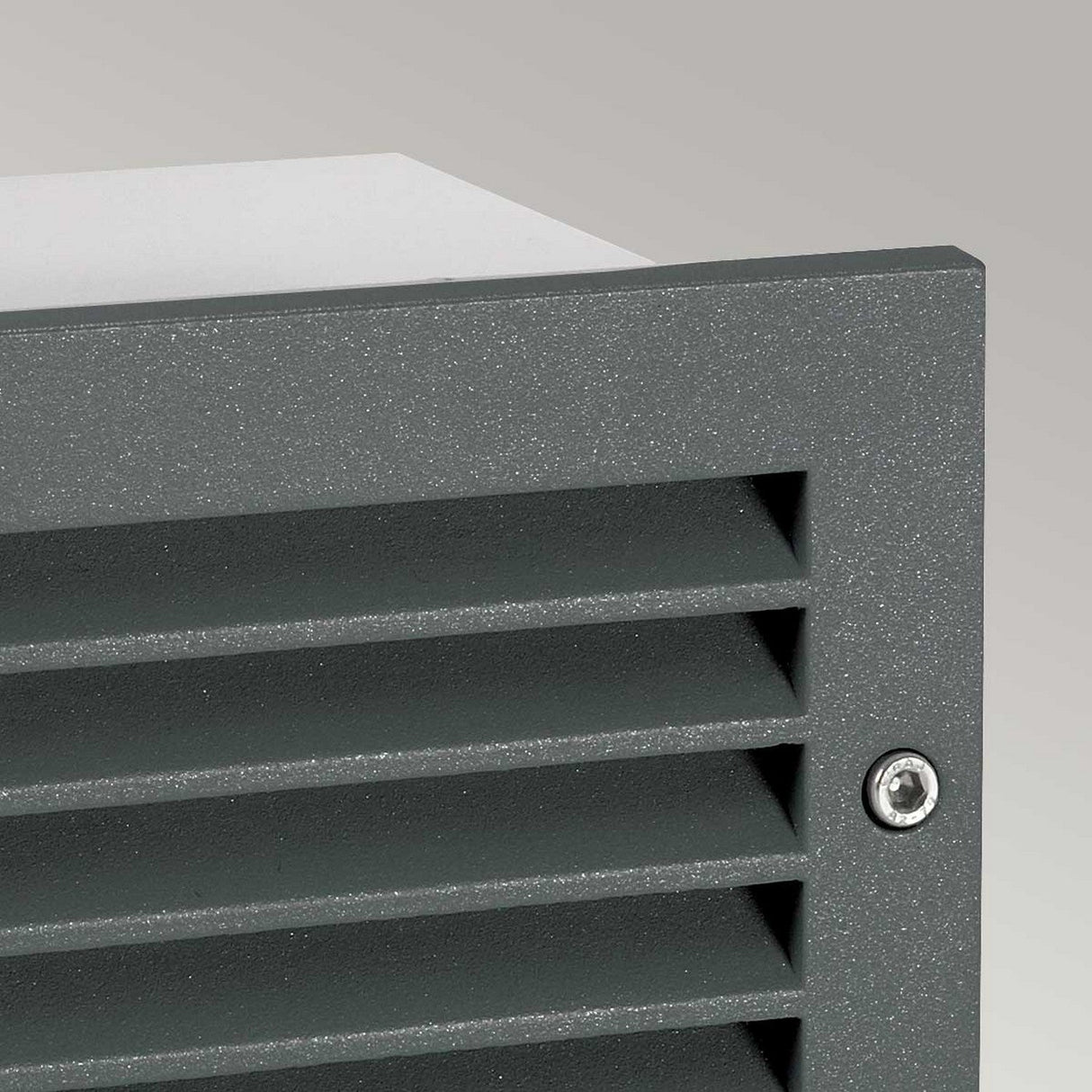 Close-up of the Grimstad LED Recessed Wall Light in graphite, featuring a sleek design with horizontal slats and a screw in one corner, set against a light gray backdrop.