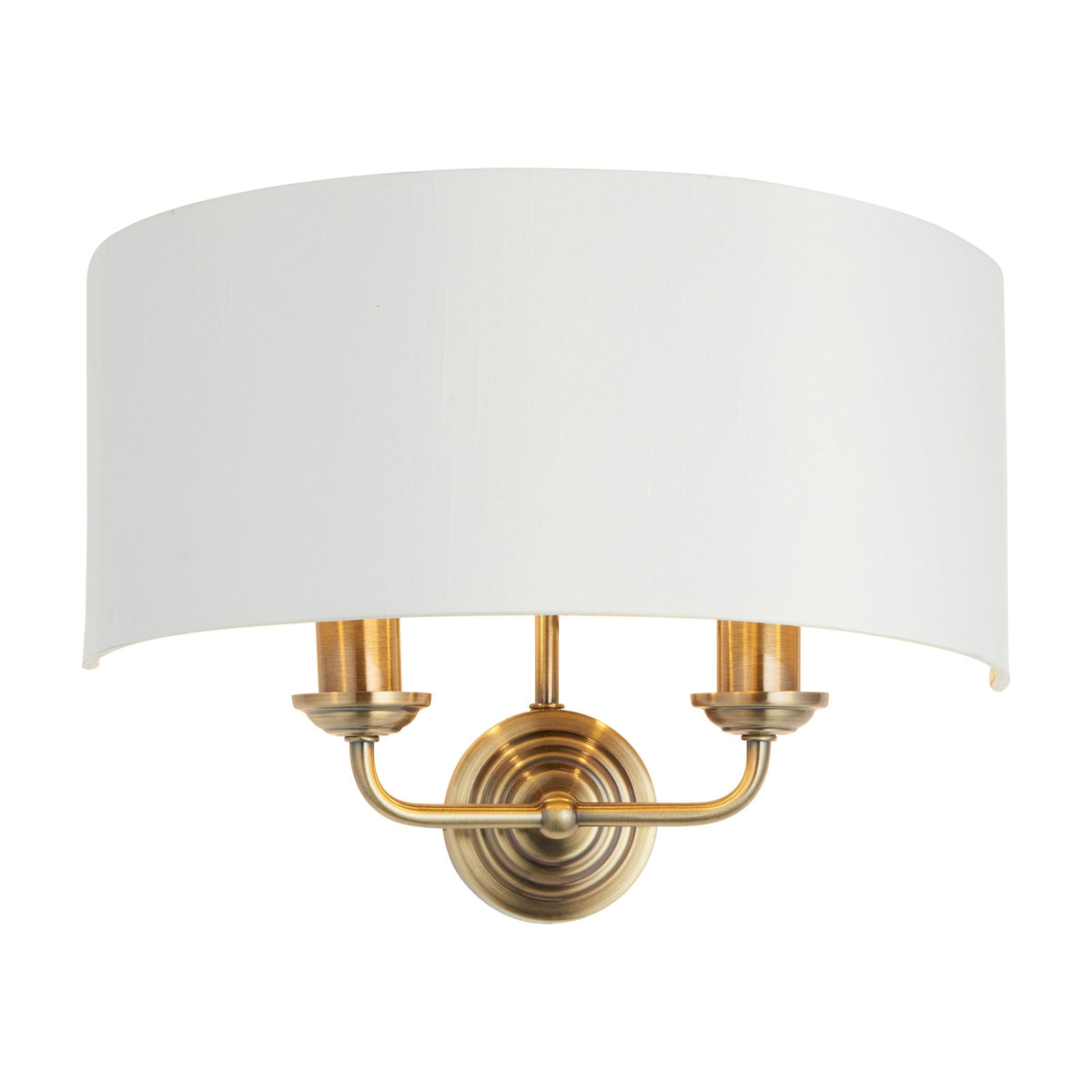 Gallery Direct Clervorne 2 Light Wall Light with antique brass twin arms, turned backplate and white half-drum fabric shade on a plain background.