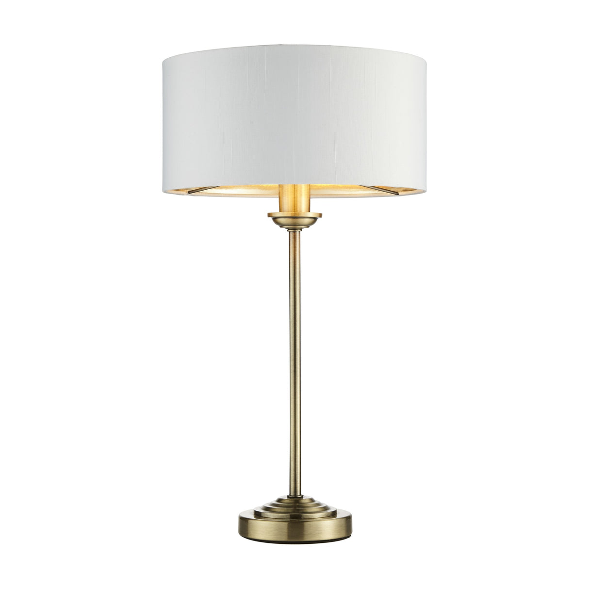 Gallery Direct Clervorne Table Lamp with slim antique brass stem, stepped base and white fabric drum shade, shown illuminated on a plain background.