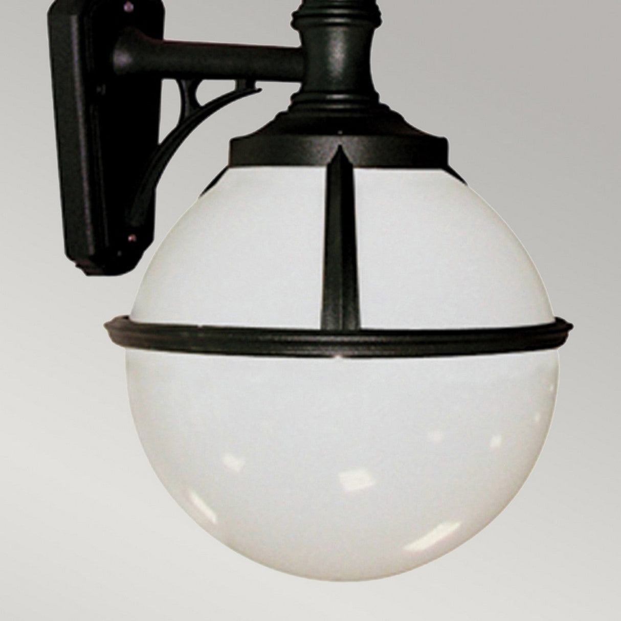 The Glenbeigh 1 Light Outdoor Wall Light in black showcases a classic round white globe design with black metal accents, mounted against a light gray background. This IP44 rated outdoor wall fixture provides even illumination through its frosted glass surface and is designed to be corrosion-proof.