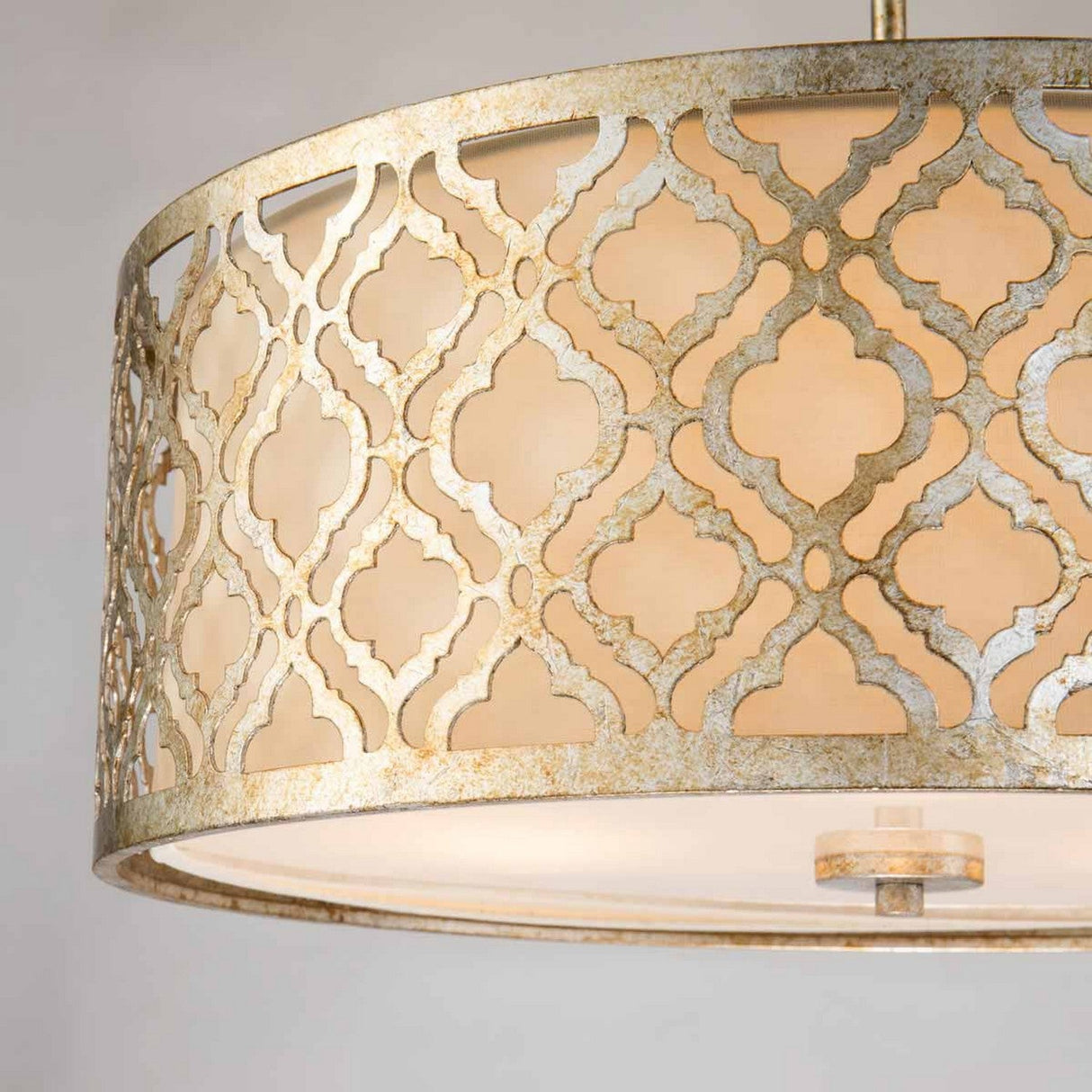 A close-up of the Arabella 3 Light Duo-Mount Large Pendant/Semi-Flush in Gold with Ivory Shade highlights an elegant gold metal structure featuring an intricate geometric pattern. The piece includes a soft, warm light diffuser, blending sophisticated and modern aesthetics to create a stylish ambiance that comfortably supports retrofit LED lamps.