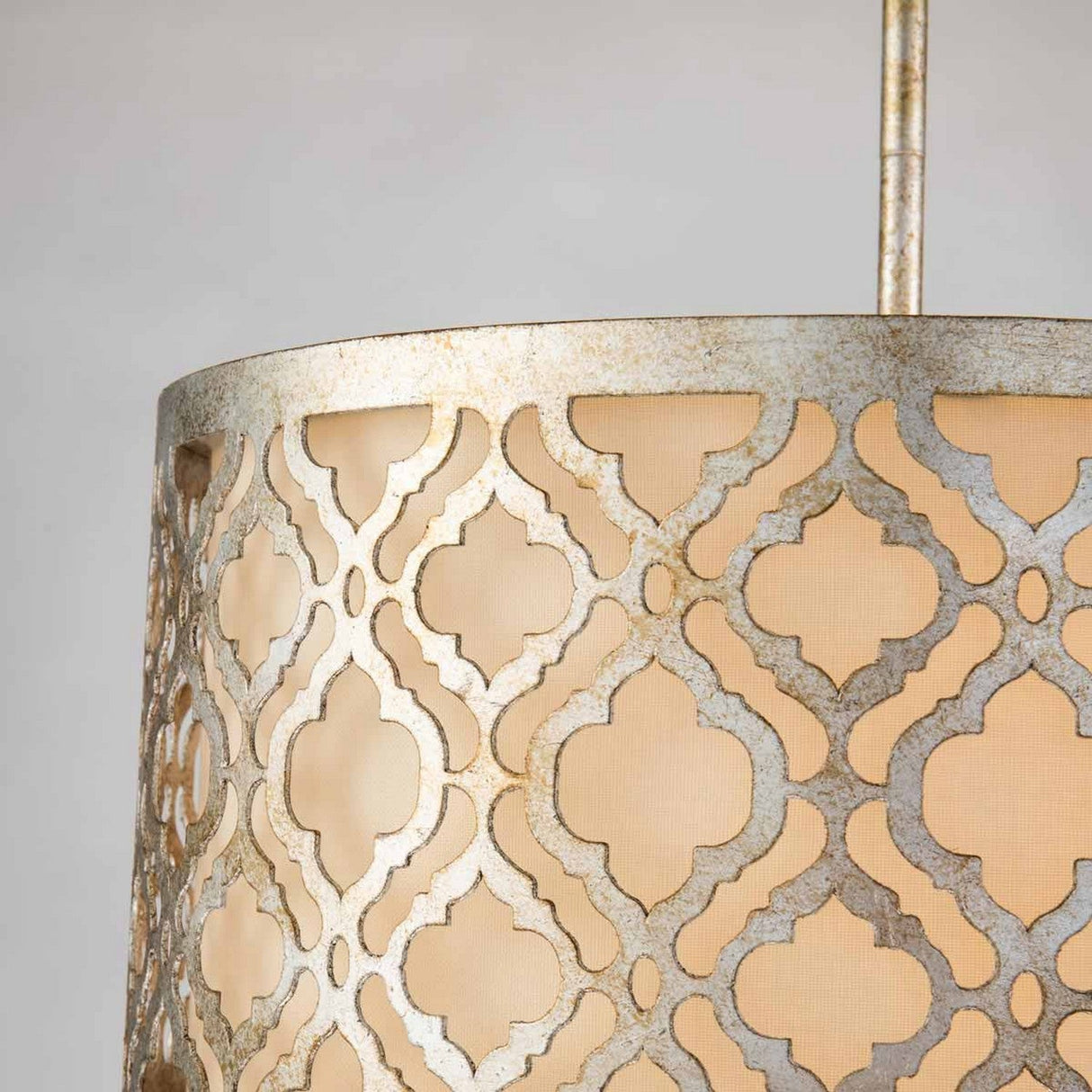 Close-up of an Arabella 2 Light Duo-Mount fixture, highlighting its semi-flush installation with a decorative metal lampshade. The geometric pattern emits a soft, warm glow from within and features a subtly weathered gold-toned finish that enhances its sophisticated design.