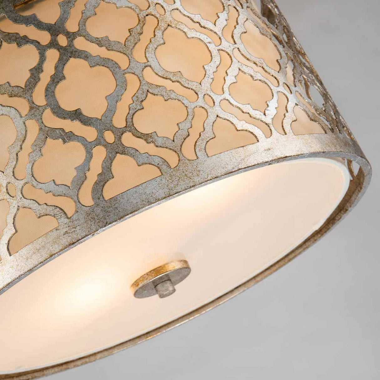 A close-up of the Arabella 2 Light Duo-Mount Medium Pendant/Semi-Flush - Gold With Ivory Shade reveals a warm glow, showcasing its metallic outer frame adorned with an intricate gold metal design. The softly illuminated interior highlights the ornate pattern against a neutral background, featuring semi-flush fittings.
