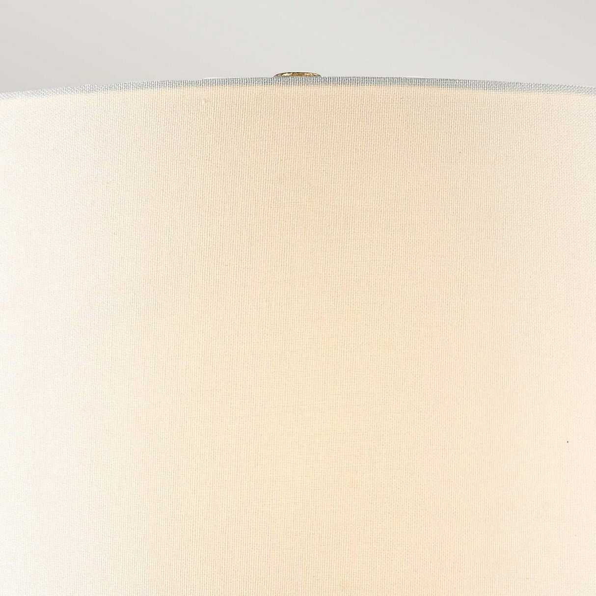 Close-up of the Arabella 1 Light Table Lamp in gold, showcasing its ivory shade against a neutral background. The textured fabric and cylindrical shape are highlighted, with a subtle view of the lampshade's top edge.