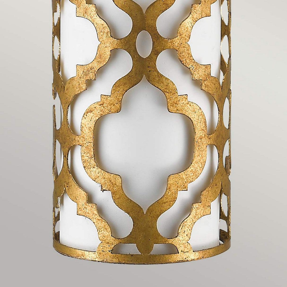 Close-up of an Arabella 1 Light Table Lamp, featuring a cylindrical white glass body embellished with an ornate gold lattice pattern. The intricate, symmetrical curved design provides a luxurious and elegant look against a gray background.