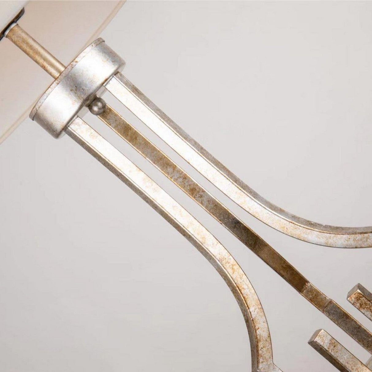 Close-up of the Lemuria 1 Light Table Lamp's ornate metallic base, featuring a brushed gold finish with a subtle Grecian key motif. The image highlights the upper section, showcasing exquisite craftsmanship against a plain white background.