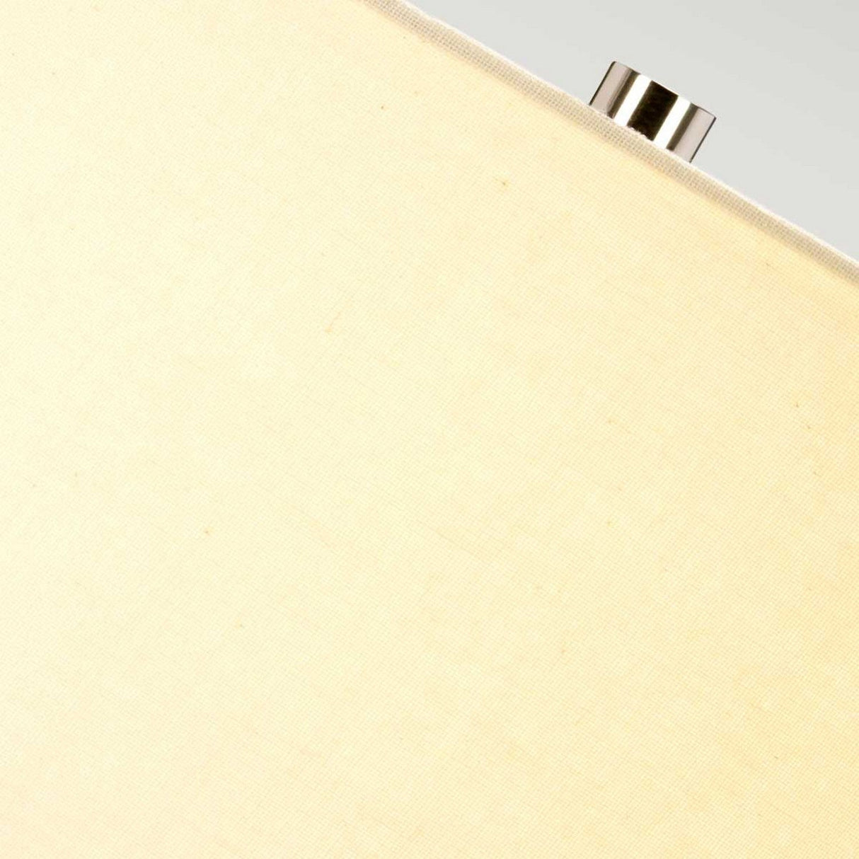 Close-up of a fabric surface in a soft grey/brown hue, possibly from a Grange Park 1 Light Table Lamp, featuring a small metallic knob extending from the top edge. The image captures ambient lighting with its gentle, neutral color tones.