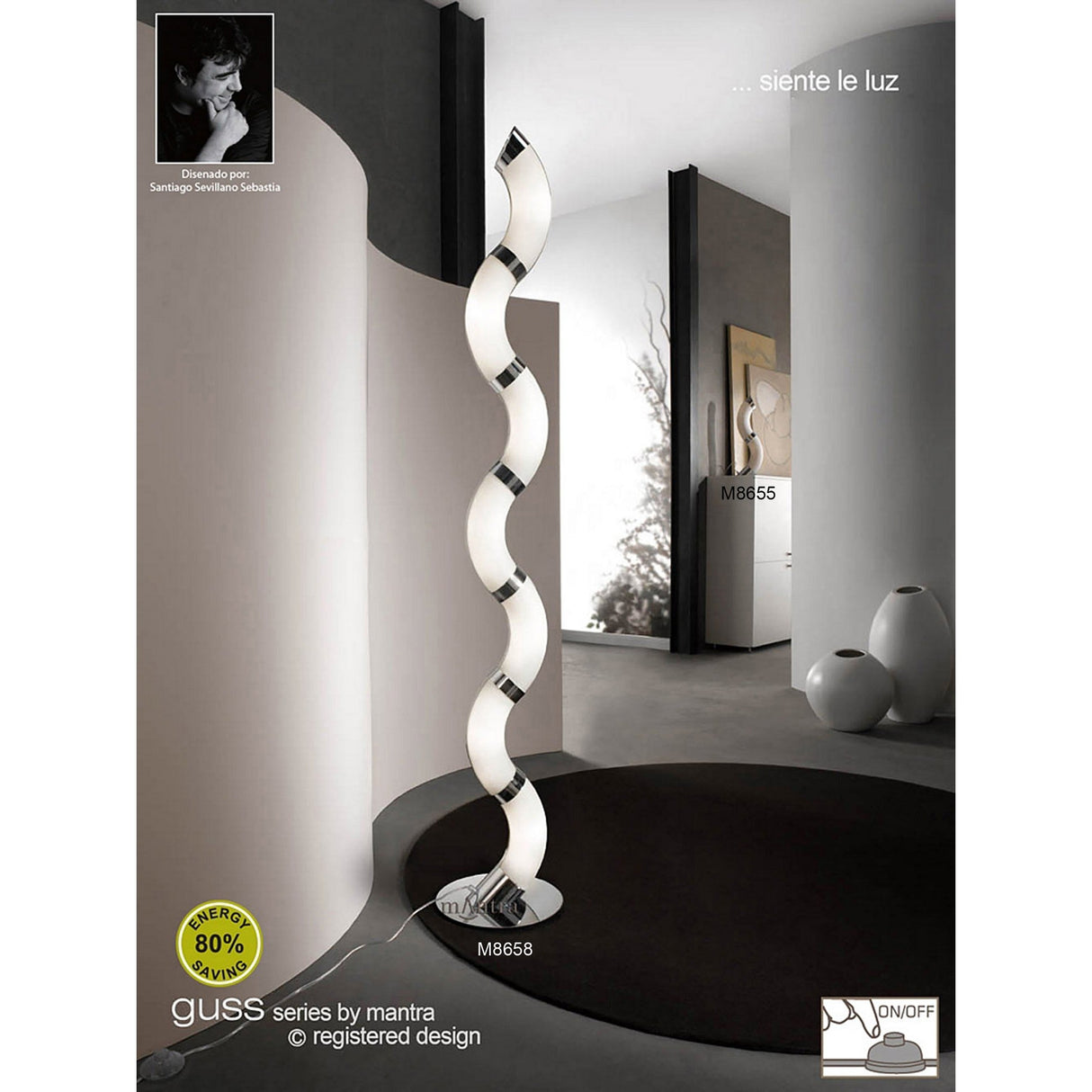 The Guss LED Table Lamp 30K 2700K in Polished Chrome with White Acrylic emits a warm white glow in a modern, minimalistic room with curved walls, abstract art, white furniture, and energy efficiency and on/off icons visible.