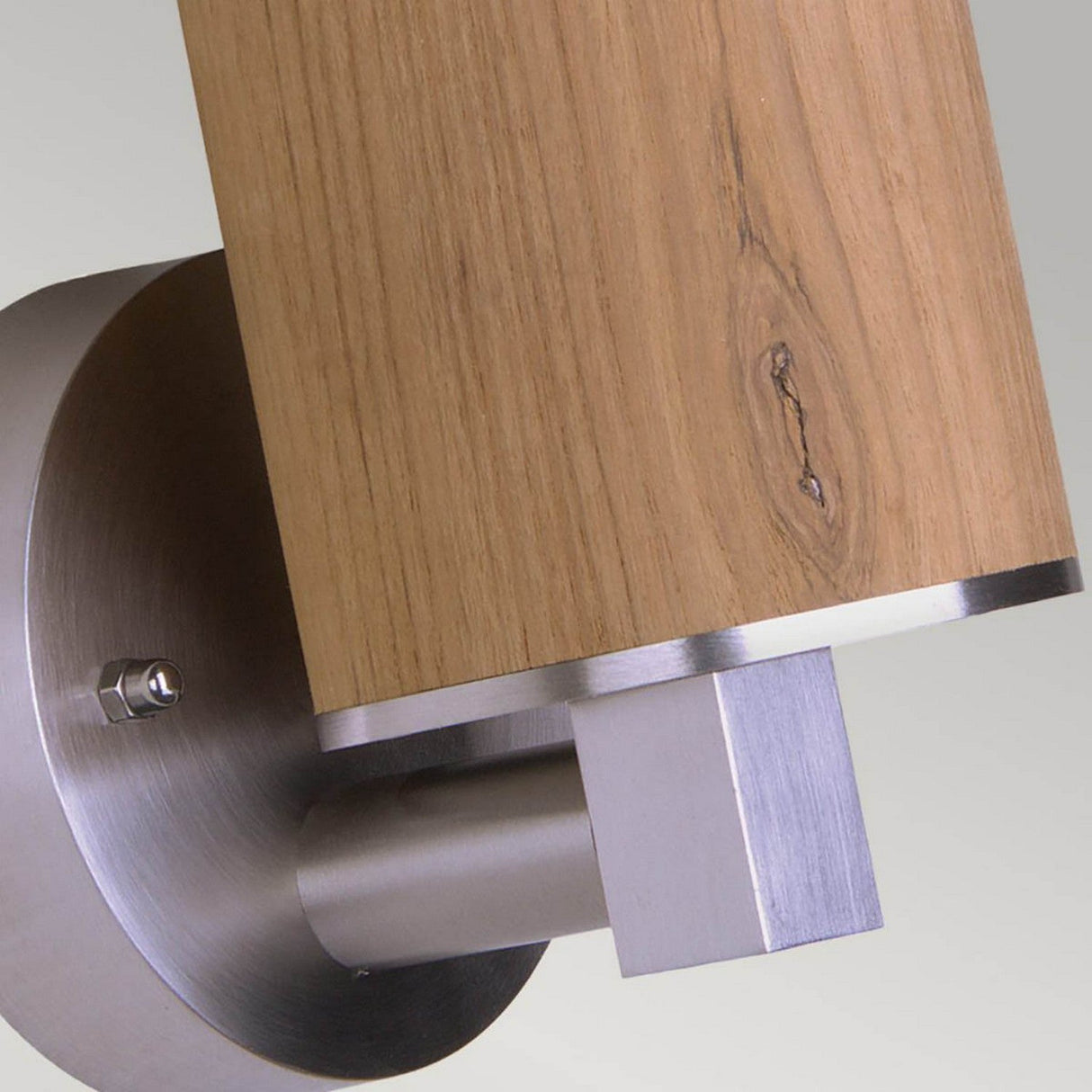 A close-up image showcases the Poole 1 Light Outdoor Wall Light - Light Brown, mounted on a wall. This modern fixture combines a cylindrical wooden accent with visible wood grain and a round, brushed marine-grade stainless steel base. With its IP44 rating, it ensures durability and exudes contemporary charm through its blend of wood and metal.