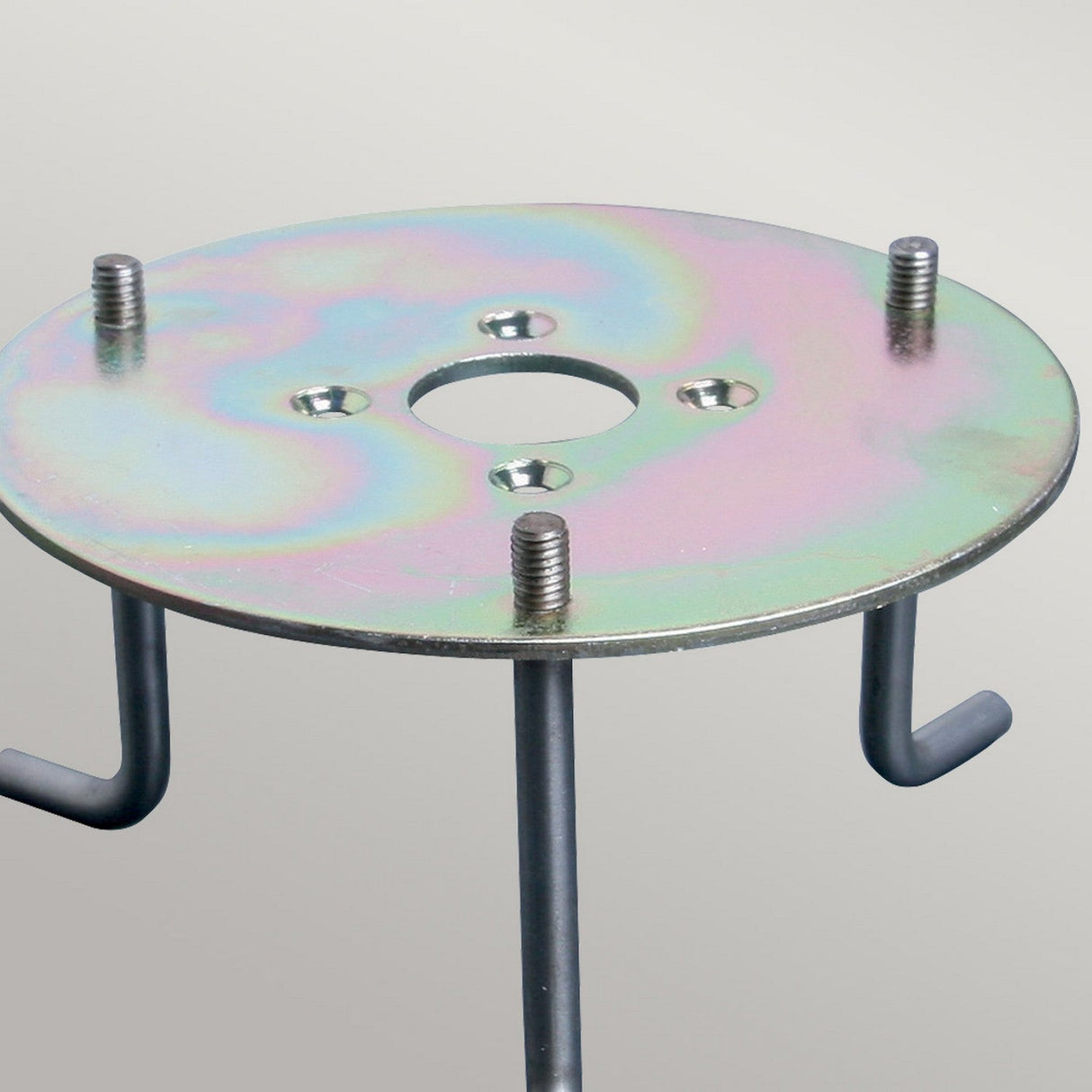 The Root for Sandbanks and Poole Bollards, a circular metal support plate, is designed with four threaded bolts and two protruding hooks to enhance outdoor lighting installations. Its iridescent finish reflects rainbow-like colors over a plain, light gray background.
