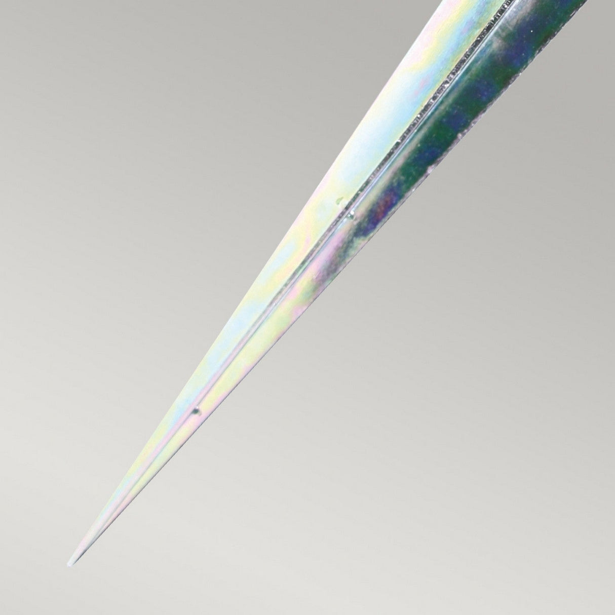 A close-up of a metallic Spike for Sandbanks & Poole Bollards on a light gray background, displaying a smooth, shiny surface with an iridescent spectrum of rainbow colors that tapers to a sharp tip, perfect for outdoor lighting applications.
