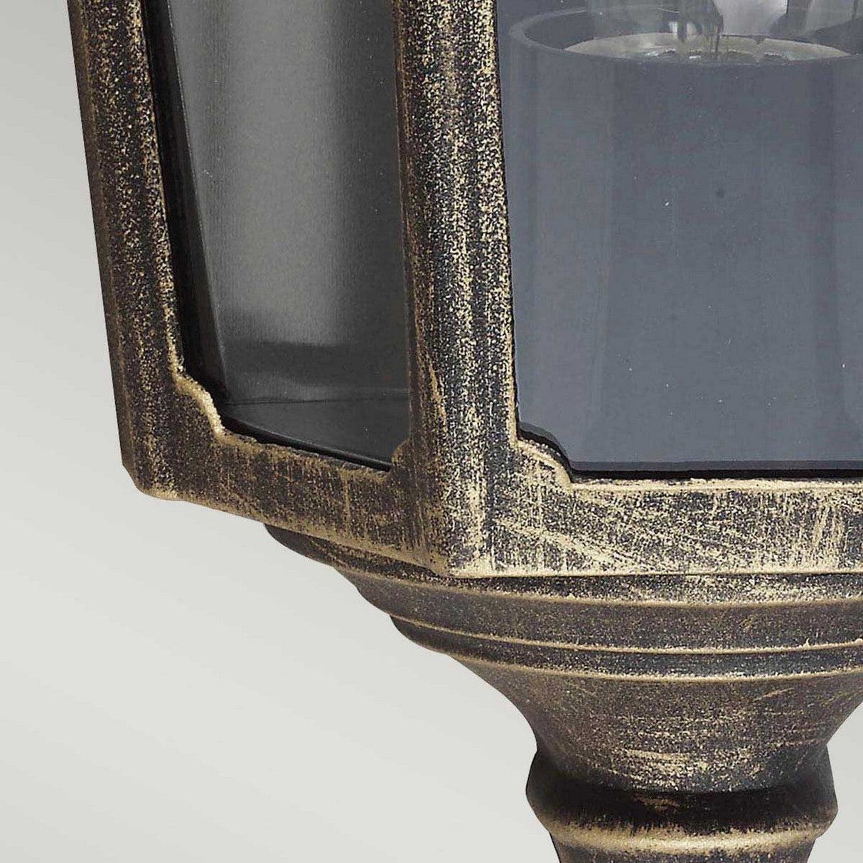Close-up of the Cricklade 1 Light Outdoor Half Lantern in a vintage style, crafted from cast aluminium with a textured, weathered black and gold finish. The lantern features glass panels and a classic octagonal shape, set against a simple gray background.