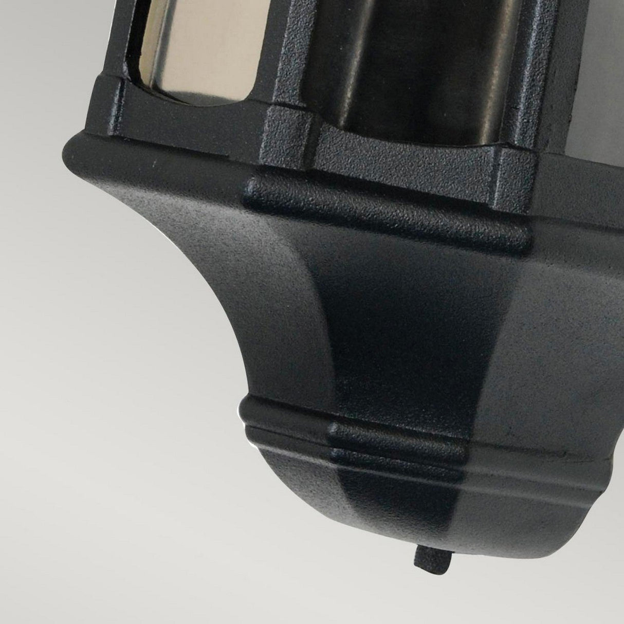 Close-up of the Newbury 1 Light Half Lantern in black, a decorative exterior lighting piece crafted from cast aluminum. Its angular design and frosted glass panels stand out against a plain light gray background, highlighting the lantern's craftsmanship and detail.