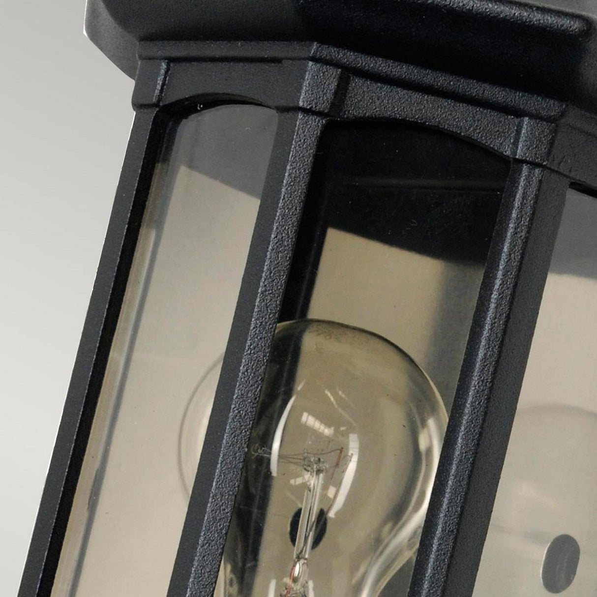 In close-up, the Newbury 1 Light Half Lantern in black features a lantern-style outdoor light fixture made from cast aluminum. This decorative exterior piece includes glass panels and a slightly curved design, showcasing the bulb's reflection—a true representation of elegance.