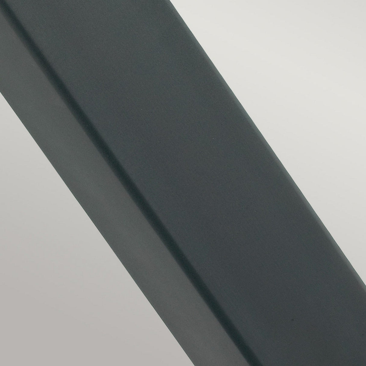 Close-up of the Halmstad 1 Light Large Bollard in black, featuring a smooth, dark gray metallic surface with a slight diagonal tilt. It reflects a gradient of light and shadow, and its weather-resistant texture appears solid and uniform, presenting a sleek and modern aesthetic ideal for outdoor lighting.