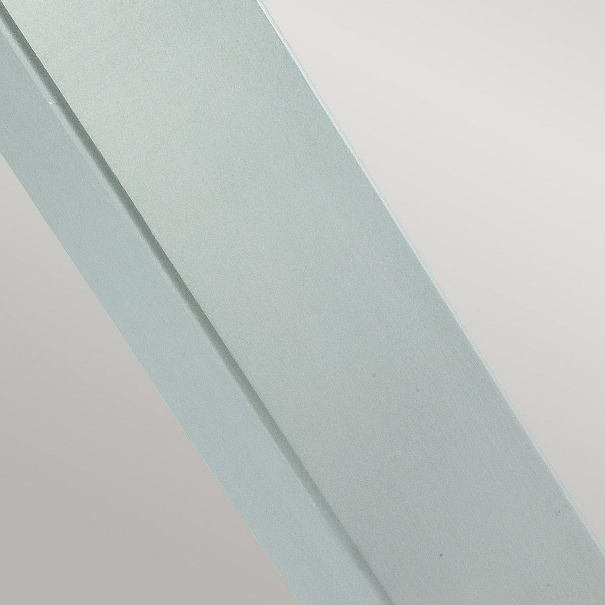 Close-up of a sleek, silver, rectangular object with a brushed texture against a pale gray background, reminiscent of the Halmstad Large Bollard - Silver used in outdoor lighting.