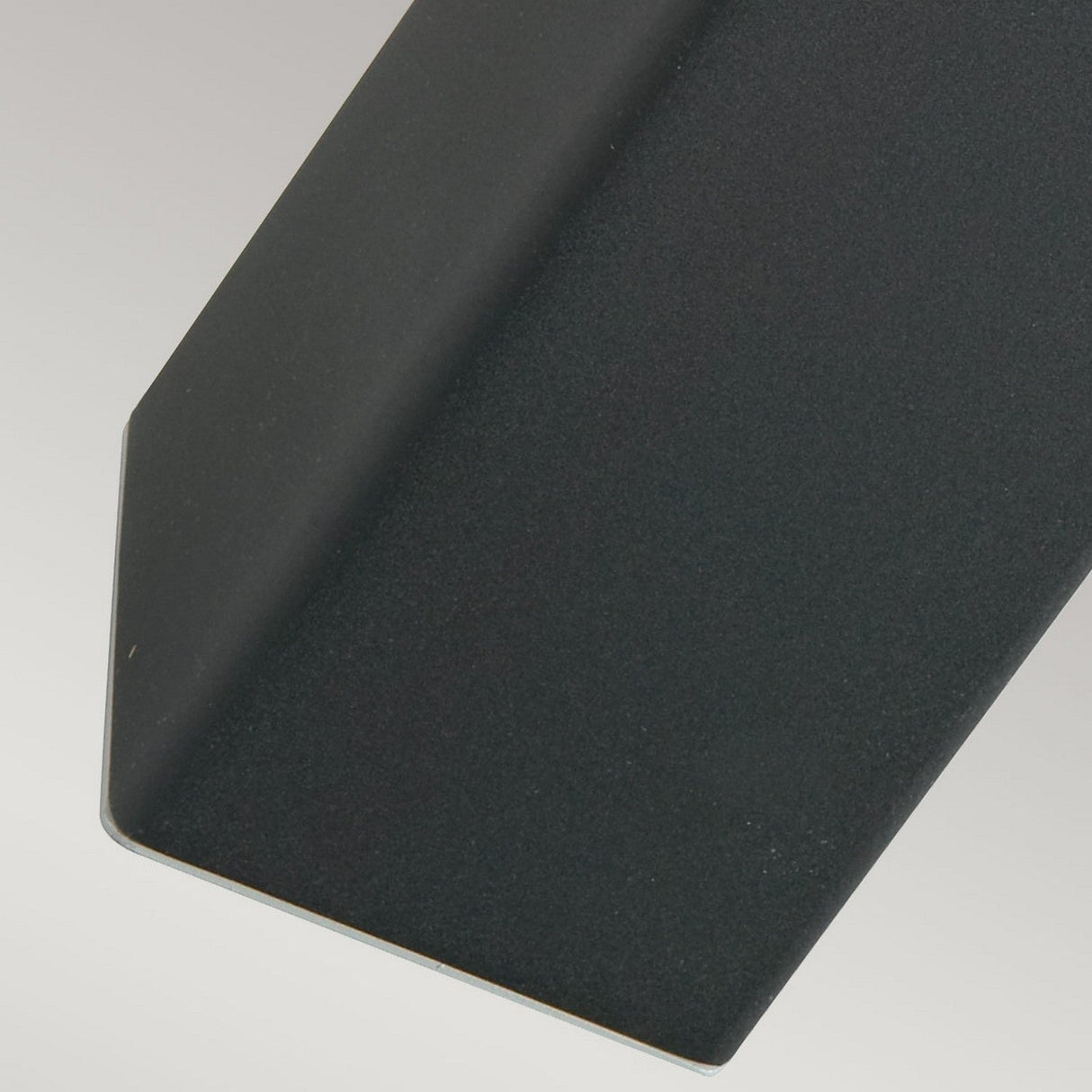 Close-up of the Halmstad 1 Light Medium Bollard in black, showcasing its geometric dark gray metal bracket or beam with a sharp angle against a light gray background, evoking contemporary design often seen in modern lighting fixtures.