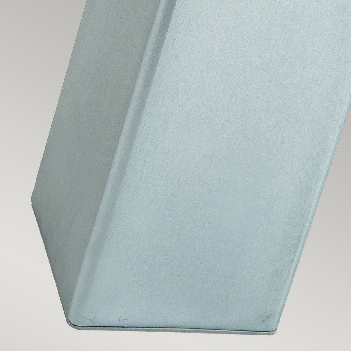 Close-up of a metallic, rectangular Halmstad Medium Bollard - Silver featuring a smooth surface with subtle texture. Made from galvanized steel, it stands against a light gray background, highlighting its sleek, contemporary design ideal for outdoor lighting.