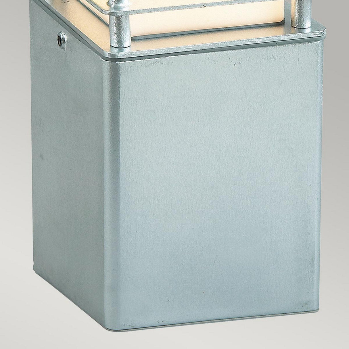 A close-up of the Halmstad Small Bollard - Silver, crafted from galvanized steel, features a smooth surface and straight edges. The top showcases a light strip flanked by two vertical metal rods, emitting a soft white glow. The plain light gray background highlights its IP65 rating for durability.
