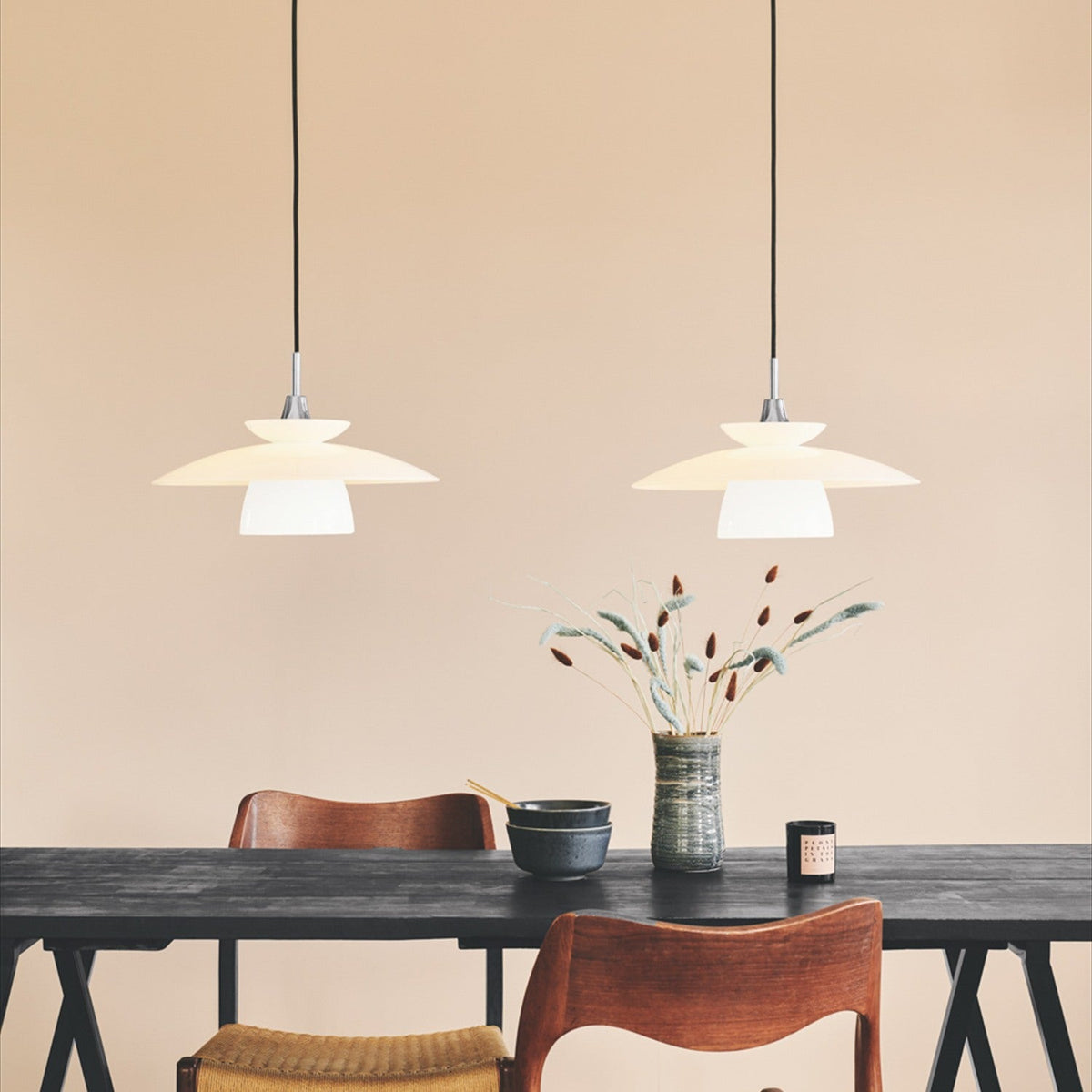 Two Scandinavia 40cm pendant lights with tiered opal glass shades and chrome fittings, hung above a dark dining table in a warm neutral room.