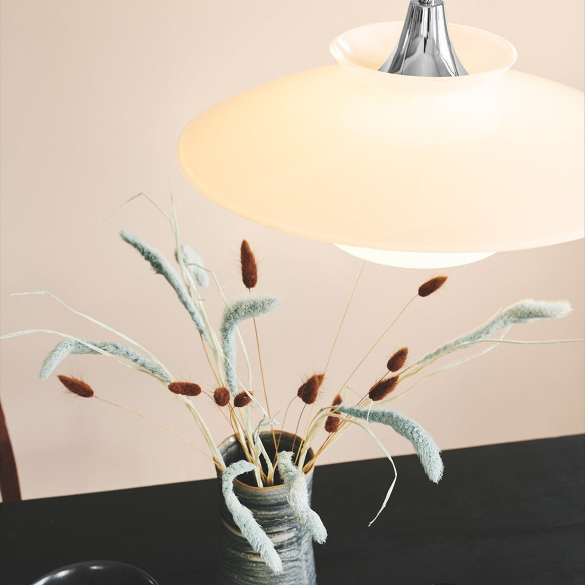 Scandinavia Pendant Light 40cm in opal glass and chrome, wide flared shade glowing warmly above a vase of dried flowers on a dark table.