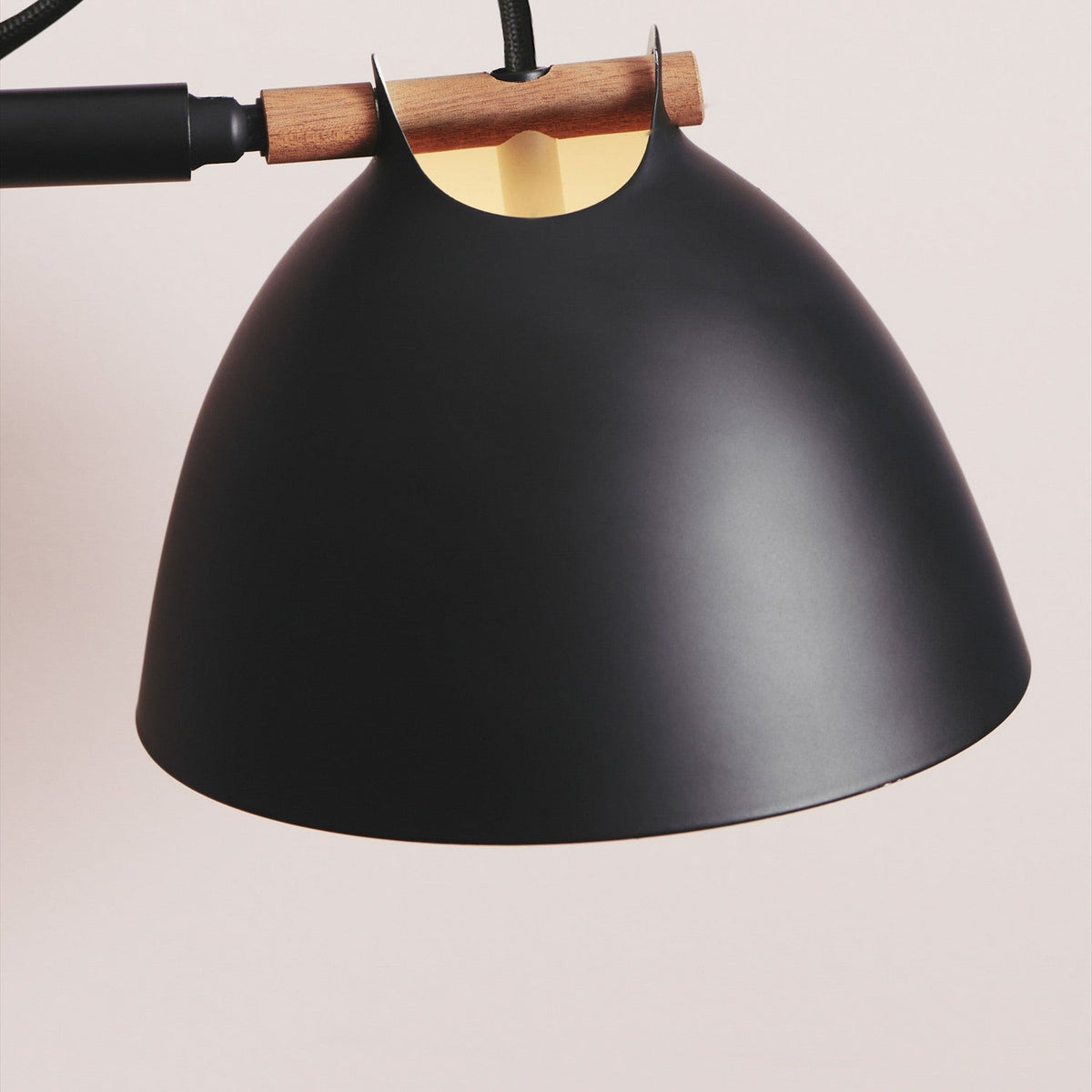 Close-up of the Aarhus 2 Light Floor Lamp's matte black cone shade with cream interior, joined to a wood arm and black stem against a plain light background.