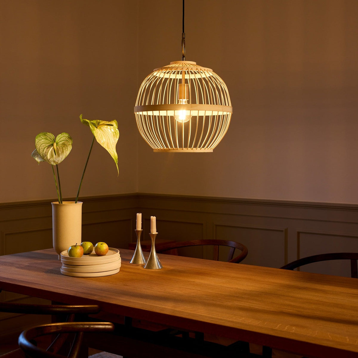 Stockholm Nordic Edition Pendant Light 40cm in natural bamboo, round woven cage shade with visible bulb, hung above a wooden dining table.