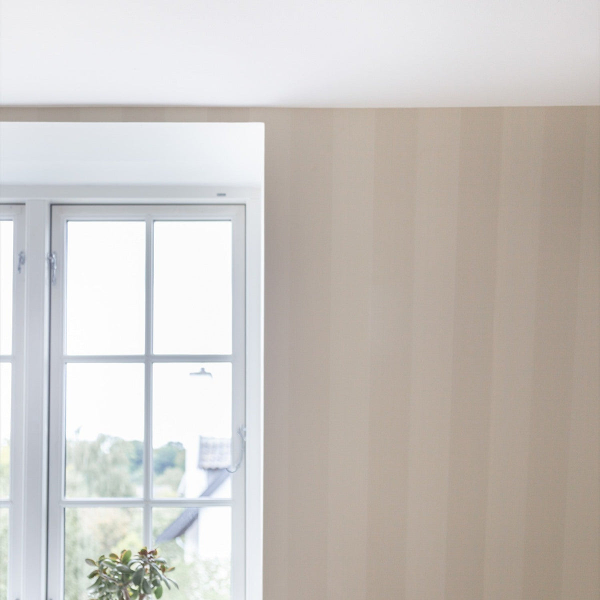 Bright window with white frame beside a wall in beige striped wallpaper, shown in a room corner with white ceiling.