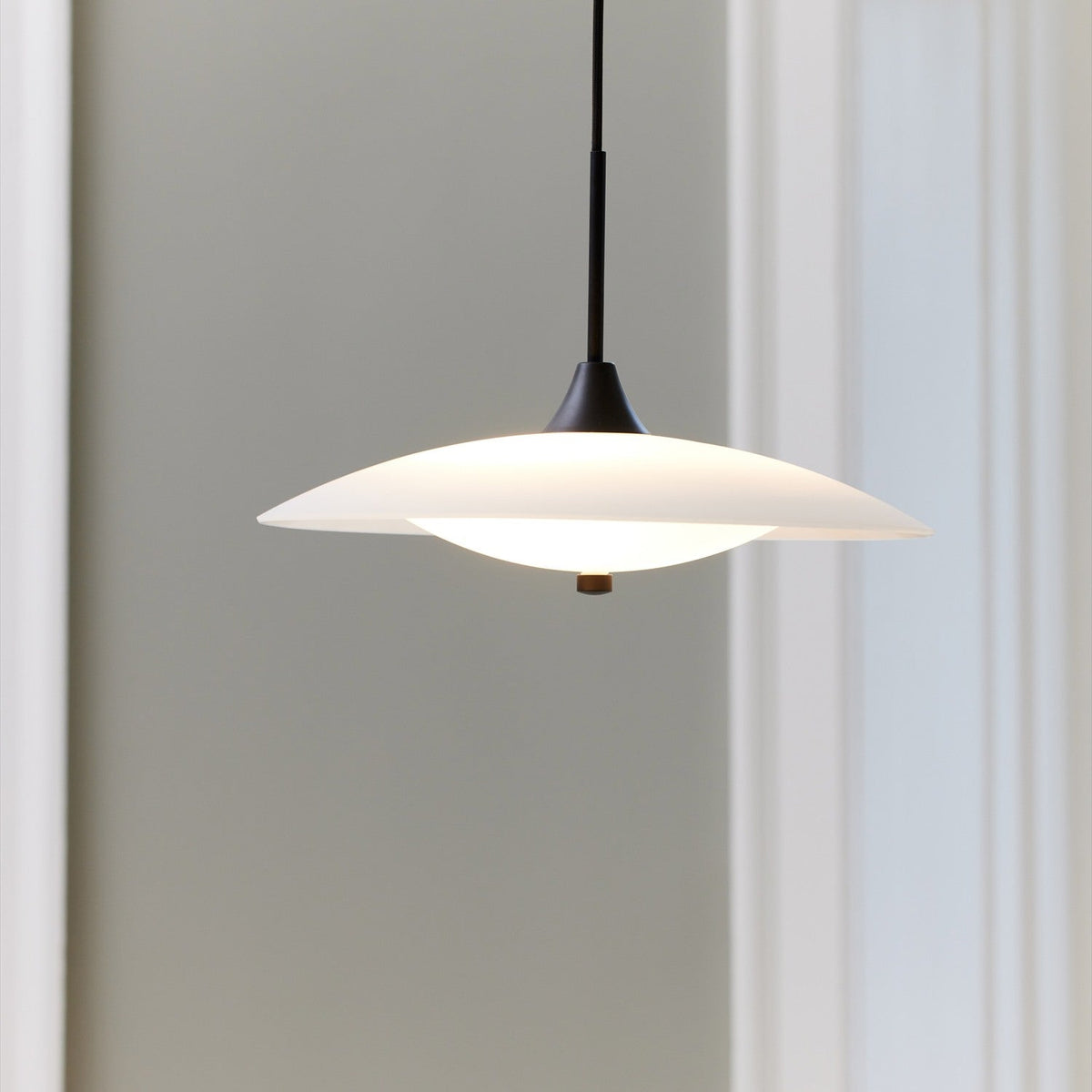 Baroni Glass Pendant Light 35cm in opal and black, wide flat white dish over a glowing opal glass bowl with black finial, hung from a black cord.