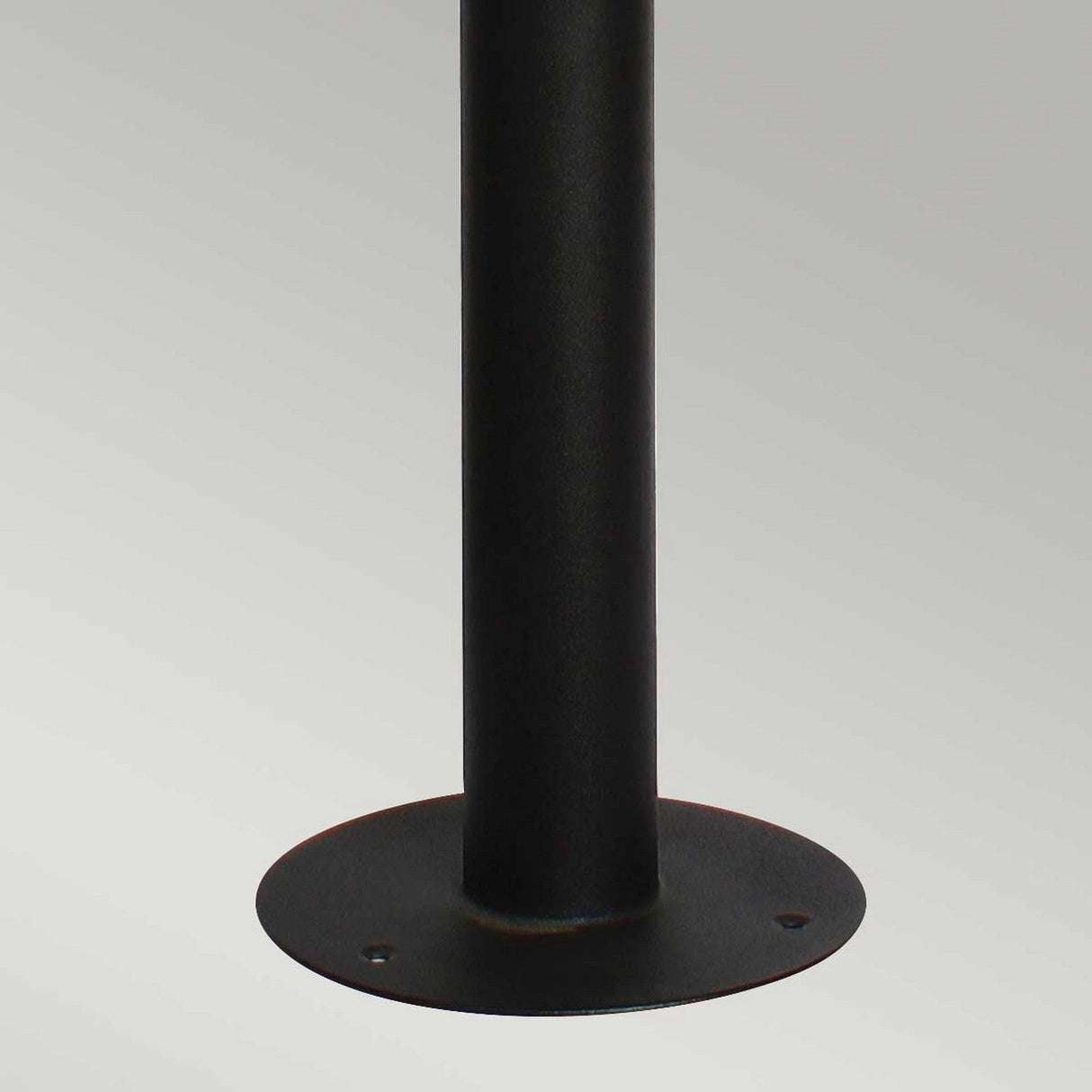 A close-up of the Helsingor 1 Light Bollard Lantern in black, featuring a round base with three holes for secure installation on surfaces, potentially in coastal environments, set against a light gray background.