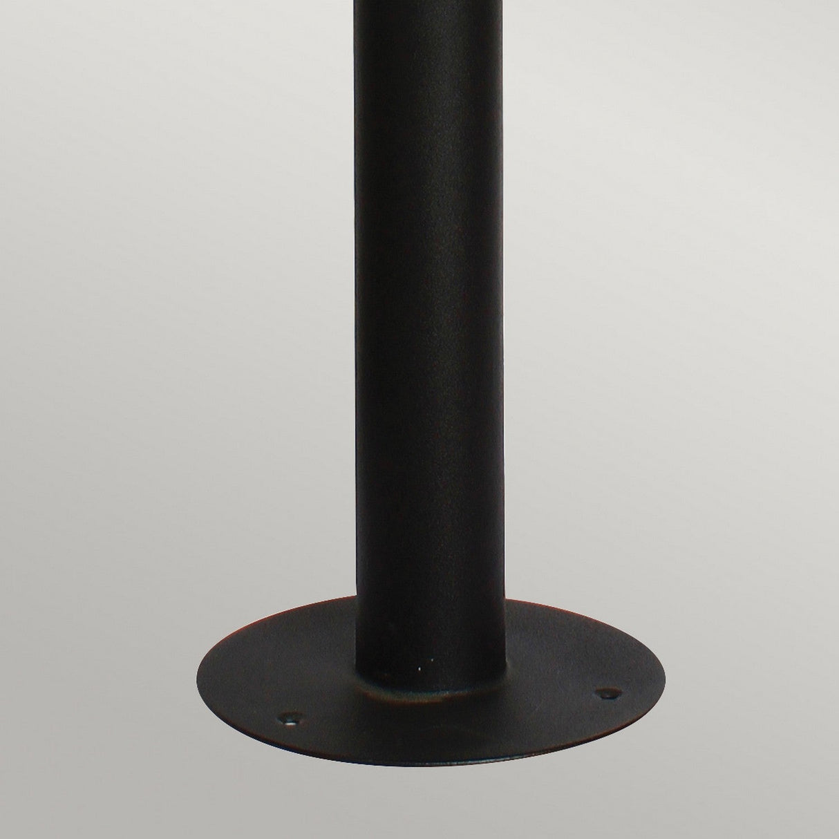 The Helsingor 1 Light Bollard Lantern with PIR in black showcases a close-up of its sleek metal base, featuring a circular flange with three mounting holes. Its sturdy design is elegantly displayed against a plain gray background.