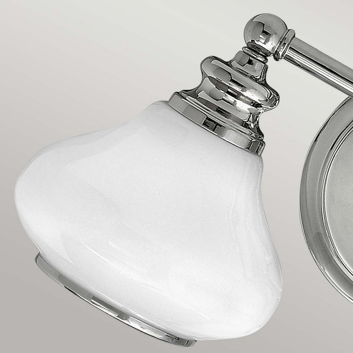 The Ainsley 2 Light Wall Light - Polished Chrome boasts a chrome wall-mounted fixture paired with a bulbous, frosted white glass shade. Its polished chrome finish offers a sleek, modern appeal similar to LED lamps, all set against a neutral gray background.