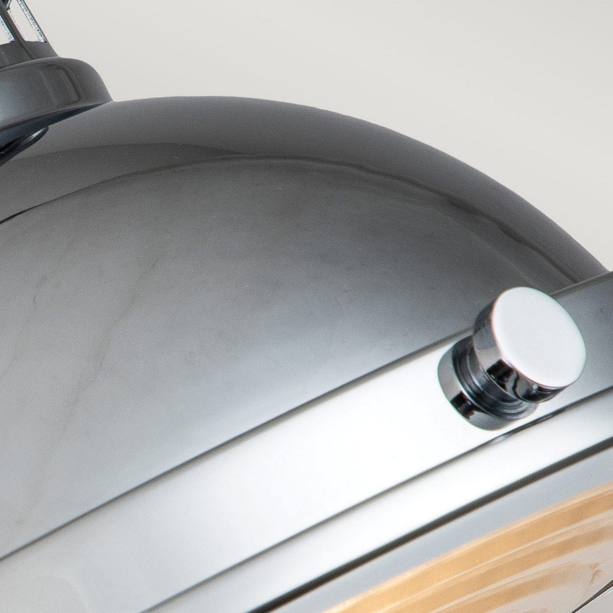Close-up of the Amelia 2 Light Flush Light in polished chrome, featuring a stainless steel dome-shaped design with a metallic knob on the side. Its surface is shiny and reflective, beautifully capturing and reflecting light from its surroundings.