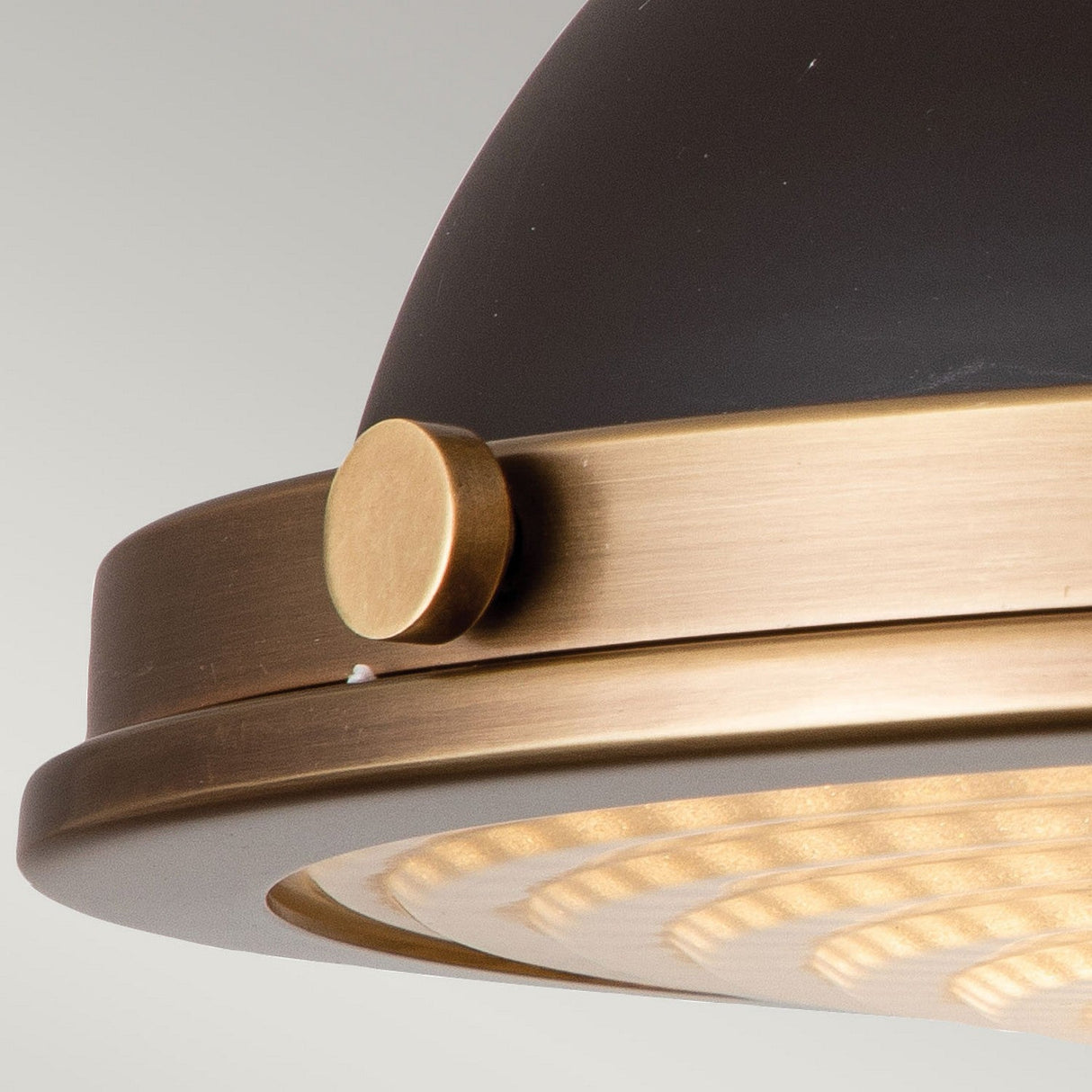 Close-up of the Amelia 2 Light Flush Light - Bronze, highlighting a vintage-style ceiling fixture with a black dome and bronze finish. It includes a brass ring and decorative knob, casting a warm glow from its ridged cast glass diffuser against a neutral background.