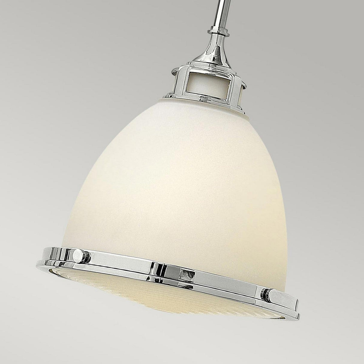 A close-up of the Amelia 1 Light Medium Pendant in chrome showcases its opal glass dome adorned with sleek chrome accents, elegantly suspended against a neutral background.