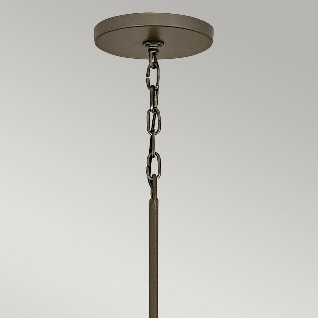 A close-up of a ceiling mount showcases the Astrid 11 Light Cluster Pendant, featuring a geometric design with a metal chain. It is suspended from a round base finished in matte bronze and gold, set against a neutral gray background.