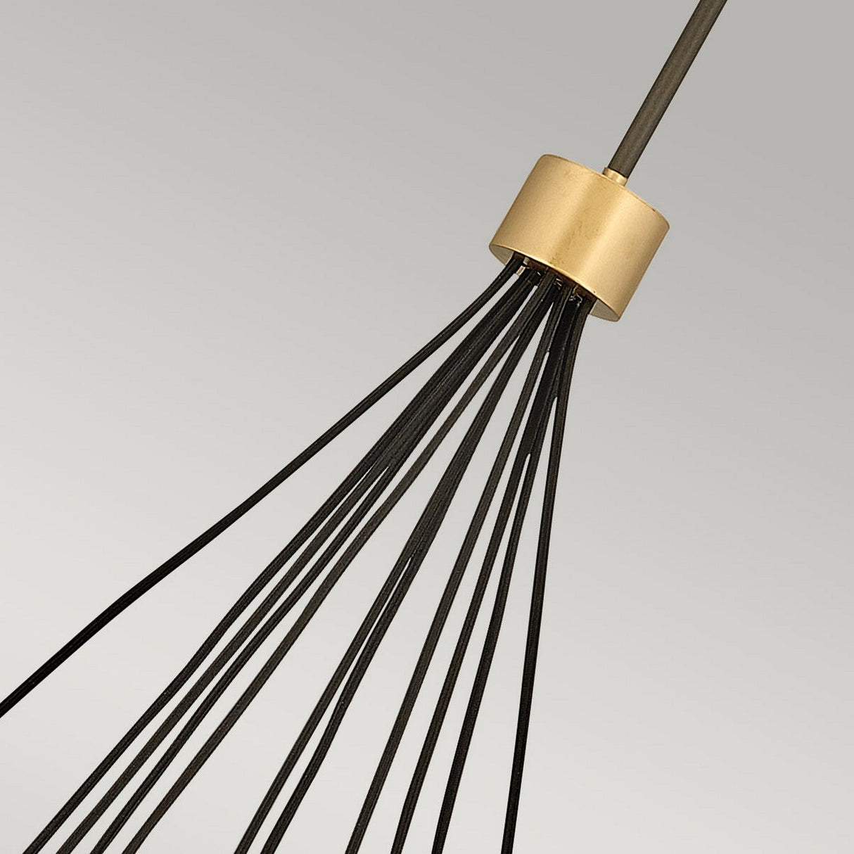Close-up of the Astrid 11 Light Cluster Pendant, featuring a modern design with numerous thin black wires extending from its matte bronze and gold cylindrical base. These wires create an elegant geometric pattern against a neutral background.